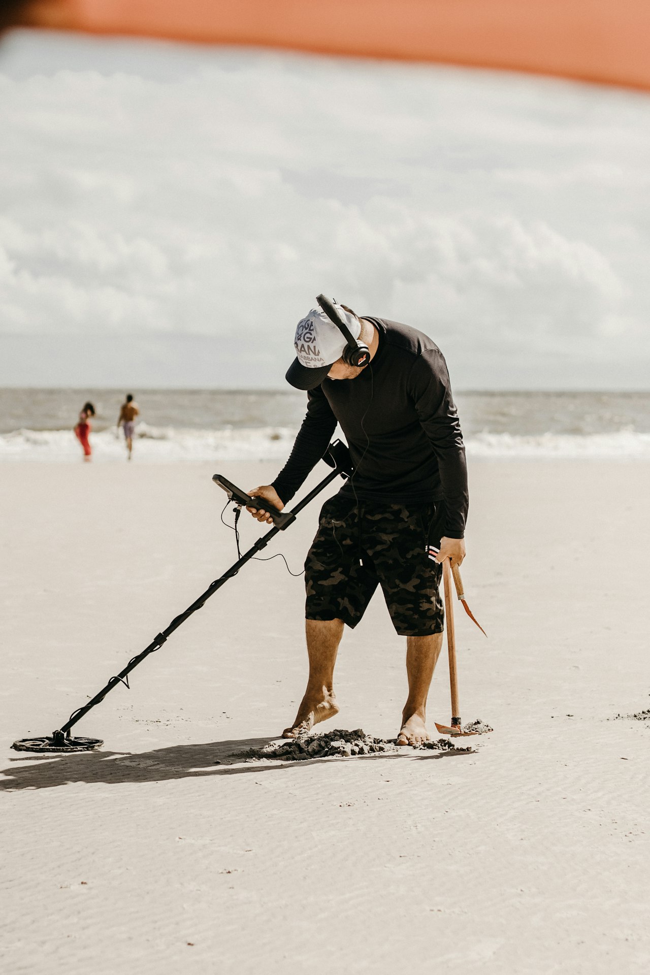 A detectorist swinging a metal detector across wet sand