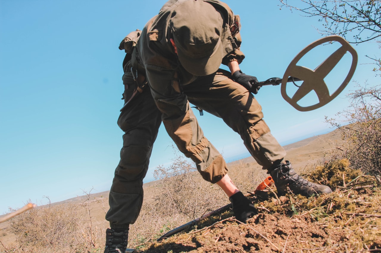 A detectorist mid-recovery on a hillside